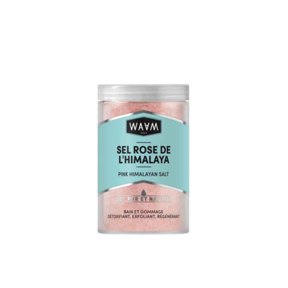 Un récipient en plastique transparent avec une étiquette bleu clair affiche « Waam Sel Rose de l'Himalaya Bain et Gommage 500 g », rempli de délicats cristaux de sel rose clair. Dakar