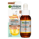 Un flacon de Garnier Skin Naturals Sérum Nuit Éclaircissant à la Vitamine C Booster d'Éclat 30 ml avec un compte-gouttes, présenté devant sa boîte. L'étiquette met en avant 10 % de vitamine C pure et présente des accents orangés. Dakar