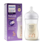 Une bouteille Philips AVENT Natural Response Biberon Motif Girafe Blanc (1 MOIS) de 260 ml remplie de lait est présentée à côté de sa boîte violette, qui met en avant les caractéristiques du produit et un charmant motif de girafe. Dakar