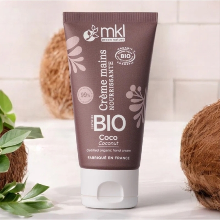 Un tube de 50 ml de MKL Crème mains certifiée BIO Coco, étiqueté en français, se trouve sur une surface blanche entourée de noix de coco coupées en deux sur un fond carrelé clair. Dakar
