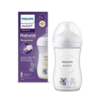 Un biberon Philips Avent Natural Response Biberon Motif Koala Blanc (3-6 Mois, 260 ml) est présenté à côté de sa boîte violette. Le biberon rempli de lait est doté d'un bouchon et d'une tétine blancs et présente d'adorables motifs de koala sur le biberon et l'emballage. Dakar