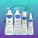 Le Pack Mustela Essentiel de Toilette Bébé, composé de quatre produits de soin pour bébé, se présente sur un fond turquoise avec une subtile illustration de baleine. Dakar