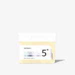 Une boîte de Numbuzin Tampon Éclaircissant Concentré de Vitamine ET Niacinamide Anti Imperfections (70 tampons), comportant une étiquette "5+", un bouchon blanc et un corps jaune clair, est présentée sur un fond blanc uni. Dakar