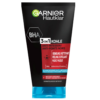 Un tube de GARNIER Pure Active Nettoyant 3 en 1 au charbon Anti-Points Noirs Incrustés 150 ml, un produit à l'étiquetage multilingue qui sert de nettoyant, d'exfoliant et de masque, a un emballage noir élégant avec un bouchon bleu, une vue familière des marchés animés de Dakar aux étagères de beauté à travers le Sénégal. Dakar