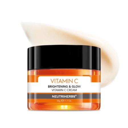 Un pot de NEUTRIHERBS Crème Boosting Vitamine C 50 ml, posé sur un tourbillon de crème en arrière-plan, présente une base orange associée à un couvercle noir élégant, soulignant ses propriétés éclaircissantes et améliorant l'éclat. Dakar