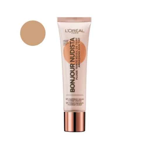 Un tube de BB crème fluide teintée Bonjour Nudista de L'Oréal Paris pour les peaux moyennes à foncées est présenté avec élégance, accompagné d'un petit échantillon de couleur beige à gauche. Inspiré du style dynamique de Dakar, le tube de 30 ml est doté d'un bouchon en or rose et d'une étiquette blanche ornée de texte orange et noir. Dakar