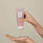 Une personne à Dakar distribuant sur sa main le Gel d'Eau aux Haricots Rouges Joseon 100 ml à partir d'un tube cosmétique rose