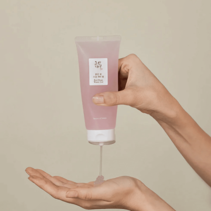 Une personne à Dakar distribuant sur sa main le Gel d'Eau aux Haricots Rouges Joseon 100 ml à partir d'un tube cosmétique rose