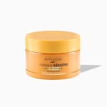 Un pot orange de 250 ml contenant le « Masque capillaire à la kératine liquide pour cheveux secs » de Byphasse est présenté sur un fond blanc, projetant une ombre vers la droite. L'étiquette du produit est clairement visible sur le devant du pot. Dakar