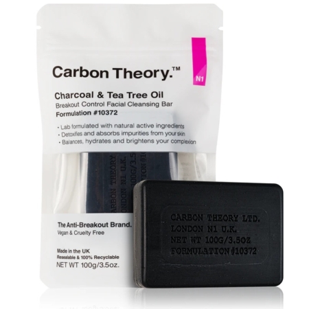 Une barre noire de Carbon Theory Savon Anti Imperfections au Charbon et à l'Huile d'Arbre à Thé 100g est présentée devant son emballage blanc, mettant l'accent sur le contrôle des éruptions cutanées et les ingrédients actifs naturels. Dakar