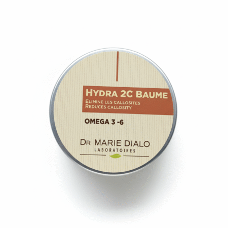 Une boîte ronde étiquetée "Dr Marie Diallo Laboratoires Baume Hydra 2C Réparatrice" comporte un texte vantant l'ultra hydratation, l'anti-taches, l'élimination des callosités (Quintos), avec des oméga 3-6. Le design du couvercle beige et marron se démarque sur le contenant de 100 ml. Dakar