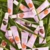 Une collection de tubes violets et blancs étiquetés « Essence Skin Tint Fond de Teint Teinté Hydratant SPF30 Finition Naturelle 30 ml » repose sur des feuilles d'aloe vera vertes. Ils présentent une gamme de nuances, mettant l'accent sur les soins de la peau et les ingrédients naturels, avec une présentation vibrante et captivante. Dakar