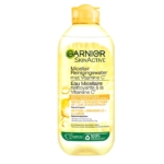 Un flacon transparent de Garnier Skin Active Vitamine C Solution Micellaire Tout en 1 400 ml, avec des accents jaunes et des textes en néerlandais et en français, est présenté sur un fond illustré d'une tranche d'agrume. Dakar
