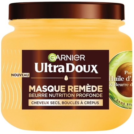 Un pot jaune de Garnier Ultra Doux Masque à l'Huile d'Avocat et Beurre de Karité, idéal pour les cheveux secs ou indisciplinés. L'étiquette met l'accent sur la nutrition en profondeur avec de l'huile d'avocat pure et du beurre de karité pour les cheveux très secs, frisés ou crépus. Dakar