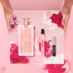 Deux mains tiennent un plateau rose et fleuri présentant le Coffret Idôle Fête des Mères Lancôme Édition Limite Eau de Parfum 50ml & 10ml plus Mascara 2.5ml, sur un fond rose. Dakar