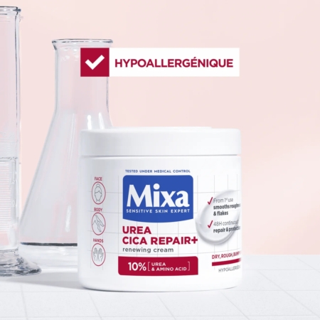 Sur une surface blanche, Mixa Urea Cica Repair Crème Régénérante Peau Sèche Rugueuse Et Inégale du Visage du Corps et des Mains 400 ml est présentée avec une verrerie de laboratoire et une coche rouge au-dessus, soulignant sa formule douce et hypoallergénique. Dakar