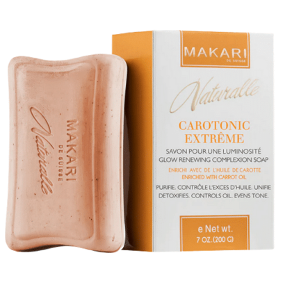 Pain de savon avec sa boîte. Le savon indique « Makari » et la boîte indique « Makari Naturalle Carotonic Extreme Savon Huile de Carotte 200g ». Coffret et savon sont beiges