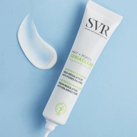 Un tube blanc de SVR Sebiaclear Mat + Pores Soin Matifiant Anti-pores dilatés 40 ml, avec un peu de crème pressée à côté, est présenté sur un fond bleu clair. Dakar