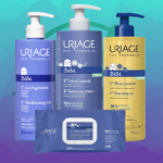 Le Coffret Kit Soins Bébé Visage Et Corps + Éponge Bain OFFERT d'Uriage présente quatre produits de soin - lait hydratant, crème nettoyante, huile nettoyante et lingettes nettoyantes - dans un emballage bleu et jaune sur fond bleu-vert. Dakar