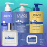 Le Coffret Uriage Kit Complet Soins Bébé + Éponge Bain OFFERT, comprenant cinq produits de soin et une éponge de bain gratuite, est présenté sur un fond dégradé bleu et vert. Dakar