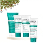 Le produit HYSEAC Routine de Soin Anti Boutons Pores Dilatés Points Noirs d'Uriage est présenté sur une plateforme blanche, agrémentée d'une branche de pin festive, de baies rouges et d'étoiles dans le coin pour une touche de fraîcheur pour les fêtes. Dakar