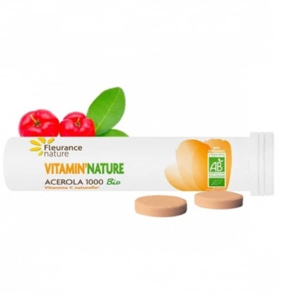 Un contenant cylindrique blanc étiqueté « Fleurance Nature Vitamine C nature Acérola 1000 Bio » avec deux comprimés ronds placés à côté. L'emballage présente une image de cerises d'acérola rouges du Sénégal avec des feuilles vertes, capturant l'essence vibrante de Dakar. Dakar