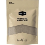 Une pochette beige refermable étiquetée « Waam Rhassoul Marocain Purifier » avec une fenêtre transparente montre une poudre grisâtre à l'intérieur ; des icônes illustrent comment utiliser ce produit de 250 g pour purifier la peau et les cheveux en absorbant l'excès de sébum et en resserrant les pores. Dakar