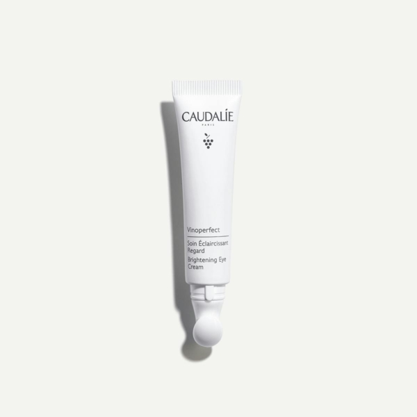 Un tube blanc de CAUDALIE Vinoperfect Soin Éclaircissant Regard 15 ml est placé verticalement sur un fond gris clair, affichant le nom et la marque du produit sur le devant. Dakar