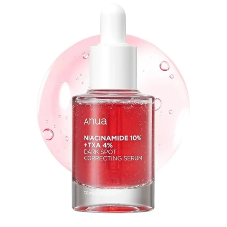 Un flacon compte-gouttes transparent étiqueté « Anua Niacinamide 10% + TXA 4% Dark Spot Correcting Serum » contenant un liquide rouge. Le flacon est placé devant un fond de gouttelettes roses. Dakar