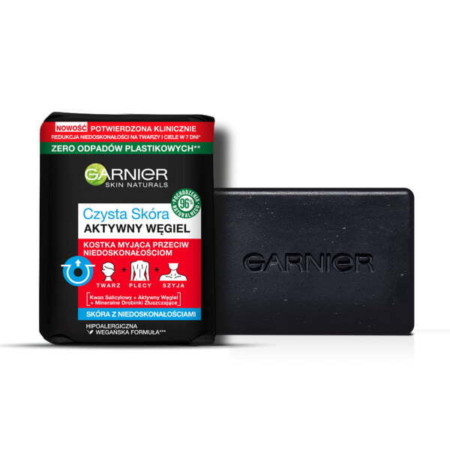 Un Garnier Pure Active Charcoal Savon Nettoyant Peaux à Tendance Acnéique 100g noir est posé à côté de son emballage, qui affiche un texte en polonais sur les bienfaits pour le visage, le dos et le cou, sans aucun déchet plastique. Dakar
