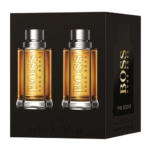 Image de l'emballage du Coffret Hommes The Scent de Hugo Boss, comprenant deux élégants flacons de 50 ml avec des bouchons foncés et un liquide ambré. « Hugo Boss The Scent » est gravé en relief en or sur les deux flacons et sur l'élégant coffret. Dakar