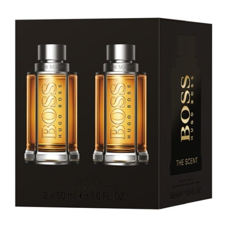 Image de l'emballage du Coffret Hommes The Scent de Hugo Boss, comprenant deux élégants flacons de 50 ml avec des bouchons foncés et un liquide ambré. « Hugo Boss The Scent » est gravé en relief en or sur les deux flacons et sur l'élégant coffret. Dakar