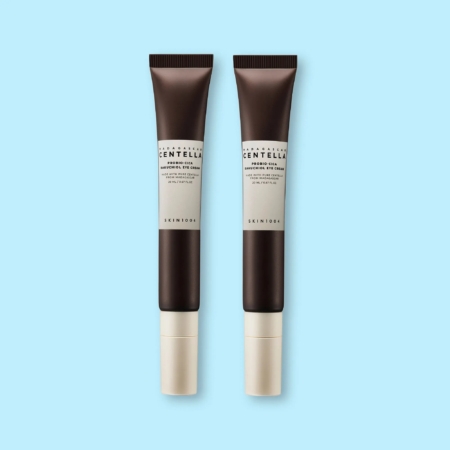 Deux tubes identiques marron foncé de SKIN1004 Madagascar Centella Probio Cica Bakuchiol Crème Yeux Anti Rides Effets Apaisants 20 ml avec des bouchons beiges, debout sur un fond bleu clair. Dakar