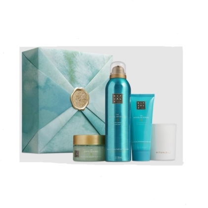 Un coffret cadeau à motifs de marbre bleu et vert avec un sceau doré est présenté à côté de quatre produits du coffret cadeau Rituals The Ritual of Karma : un pot, un grand flacon pulvérisateur, un tube et une bougie blanche. Dakar