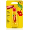 Le Baume à lèvres CERISE de Carmex se présente dans un petit tube souple avec un bouchon rouge. Son emballage cartonné jaune comporte des images de cerises et un texte multilingue soulignant ses bienfaits hydratants SPF 15. Dakar