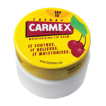Un contenant rond et jaune de baume à lèvres hydratant FPS 15 de la marque Carmex Le pot cerise présente une illustration de cerise sur le couvercle, indiquant « Il apaise. Il soulage. Il hydrate. » Visitez mycarmex.com pour plus d'informations. Dakar