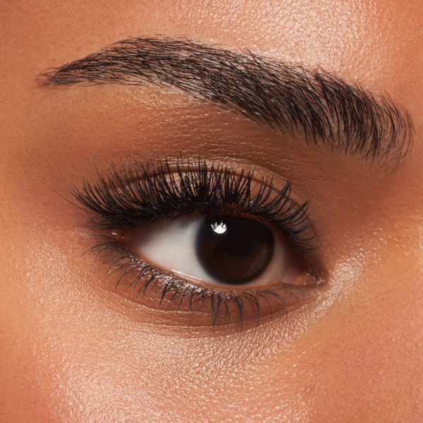 Gros plan de l'œil d'une personne, rehaussé de faux cils prédécoupés Essence Cosmetics Lashes to Impress. Le sourcil est bien coiffé, les cils sont longs et définis et la peau a une texture lisse avec un éclat naturel. Dakar