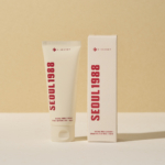 Un tube et une boîte de KSECRET SEOUL 1988 Séoul 1988 Crème Hydratante Snail Mucin 93% + Rice, avec un texte rouge en gras, se détachent sur un fond beige clair. Le tube est légèrement en avant de la boîte, projetant une ombre douce. Dakar
