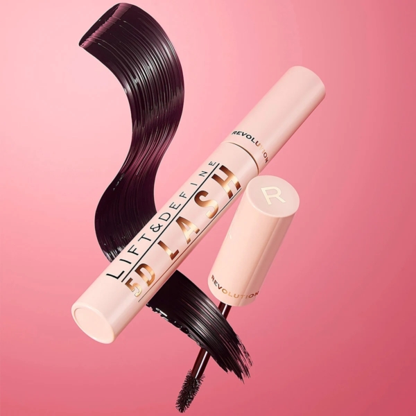 Un tube rose ouvert de mascara 5D Lash Mascara Lift and Define de 14 ml de MakeUp Revolution, ressemblant au look Lash Sensational Sky, révèle la brosse. Des volutes de mascara artistiques ornent le fond, tandis que le mot « Revolution » apparaît avec audace sur le tube sur un fond rose. Dakar