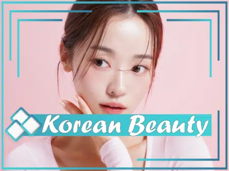 Une personne à l'expression douce pose sur un fond rose, touchant son menton d'une main. Le texte se superpose à l'image, indiquant « Korean Beauty » en police stylisée. L'image présente une bordure décorative avec des accents bleu sarcelle et blancs. Dakar