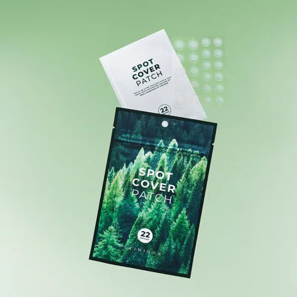 Deux paquets de patchs de protection contre les taches sur fond vert clair. Un paquet est ouvert, révélant des patchs ronds transparents. Le devant des paquets affiche une image de forêt et le texte « Spot Cover Patch ». Dakar