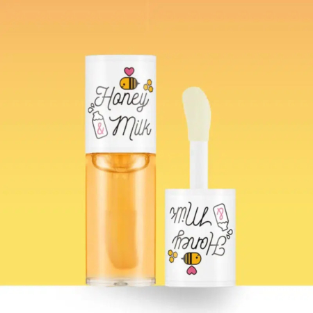 Tube de gloss à lèvres étiqueté « Honey & Milk » avec des illustrations d'abeilles et de bouteilles de lait sur un fond jaune dégradé. Le gloss est partiellement ouvert, laissant apparaître l'applicateur. Dakar