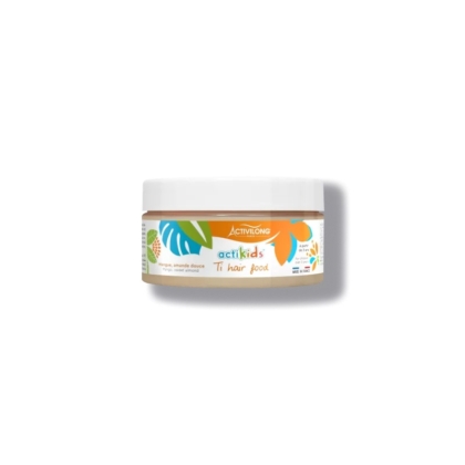 Un contenant rond de nourriture capillaire Actikids Ti d'Activilong. L'étiquette colorée, ornée de motifs de feuilles abstraits et d'un texte, indique que le produit est enrichi en mangue et en avocat. Le couvercle est blanc et le contenant projette une légère ombre. Dakar