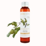 Un flacon transparent d'Huile d'Amla BIO Aroma Zone 100 ml arbore une étiquette ornée de branches d'Amla et de fruits verts, révélant la teinte ambrée de l'huile. À proximité, une image capture une branche d'Amla et des fruits, encapsulant l'essence de cette huile. Dakar