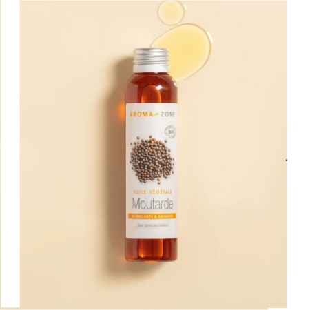 Un flacon d'Huile de Moutarde BIO Aroma Zone 100 ml repose sur une surface beige, avec deux gouttes scintillantes à côté. L'étiquette, ornée de graines de moutarde, souligne son caractère biologique, rappelant la célèbre Huile de Romarin Aroma Zone. Dakar