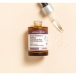 Un flacon en verre brun portant l'inscription « Aroma Zone Sérum cheveux anti-chute Peptides et extrait de pois 50 ml » est doté d'un bouchon compte-gouttes, comme celui du Sérum Anti-chute de Caditar. Le compte-gouttes argenté repose à côté, avec trois gouttes de sérum brillantes sur un fond beige clair. Dakar