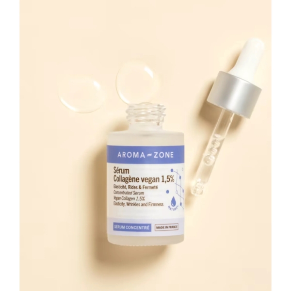 Un flacon en verre transparent, étiqueté « Aroma Zone Sérum concentré Collagène vegan 1,5 % 30 ml », muni d'un bouchon compte-gouttes, repose sur une surface beige. Deux gouttes de sérum soulignent son action sur l'élasticité, les rides et la fermeté. Découvrez le Sérum concentré Niacinamide d'Aroma Zone pour un éclat sublimé. Dakar