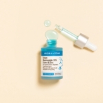 L'Aroma Zone Sérum concentré Niacinamide 10%, Cuivre et Zinc 30 ml repose sur une surface beige, faisant écho à l'Aroma Zone Elixir de fleurs précieuses de Rose. Son flacon et son compte-gouttes turquoise suggèrent une symphonie florale dans chaque goutte. Dakar