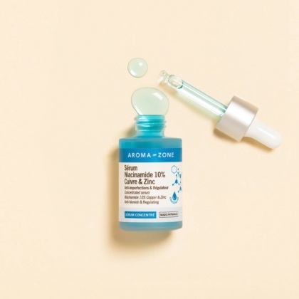 L'Aroma Zone Sérum concentré Niacinamide 10%, Cuivre et Zinc 30 ml repose sur une surface beige, faisant écho à l'Aroma Zone Elixir de fleurs précieuses de Rose. Son flacon et son compte-gouttes turquoise suggèrent une symphonie florale dans chaque goutte. Dakar