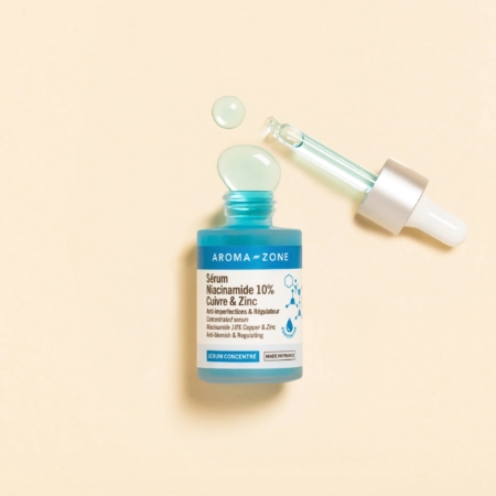 L'Aroma Zone Sérum concentré Niacinamide 10%, Cuivre et Zinc 30 ml repose sur une surface beige, faisant écho à l'Aroma Zone Elixir de fleurs précieuses de Rose. Son flacon et son compte-gouttes turquoise suggèrent une symphonie florale dans chaque goutte. Dakar